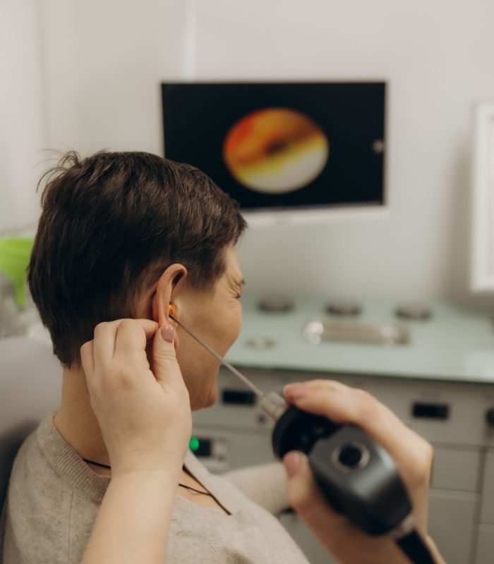 Hearing exam for elderly citizen people. Otolaryngologist doctor checking mature woman's ear using otoscope or auriscope at medical clinic